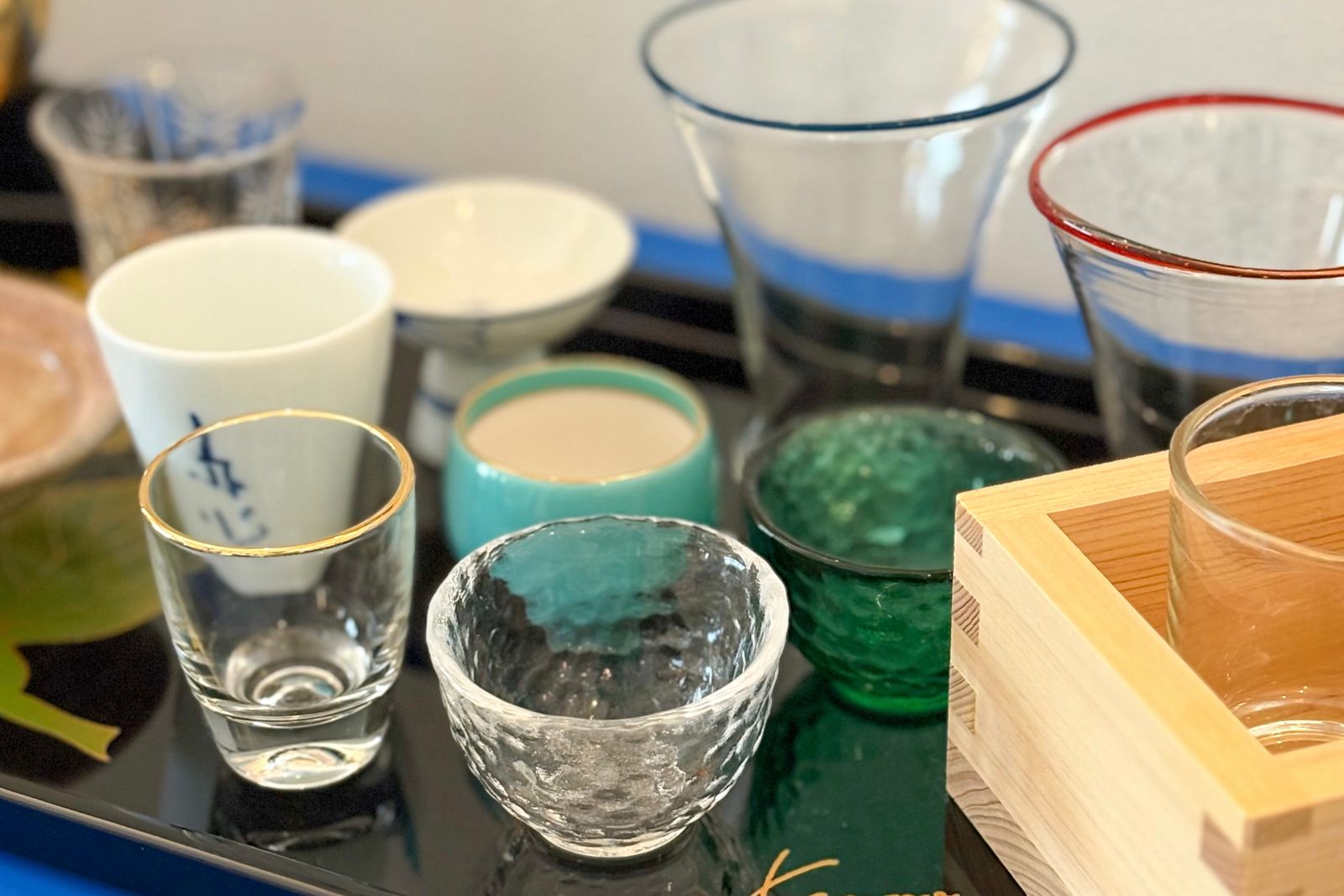 Eight small Japanese drinking vessels arranged on a lacquer tray.
