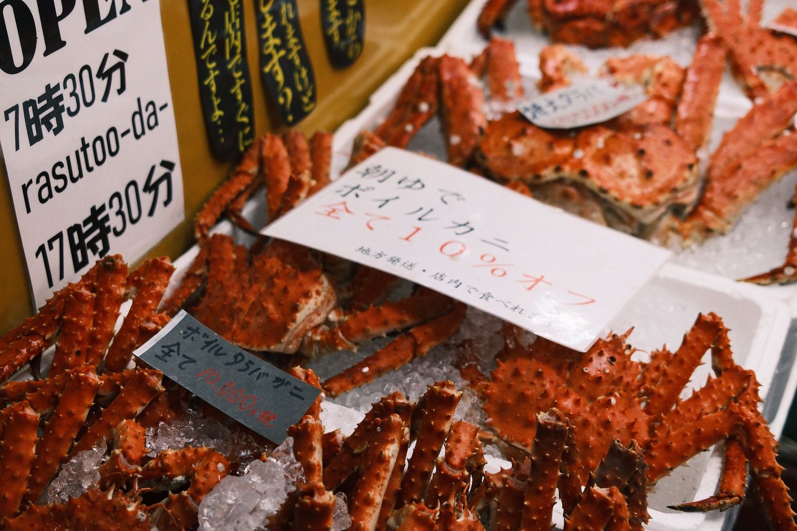 Boiled king crabs on crushed ice in styrofoam boxes at a market stall.