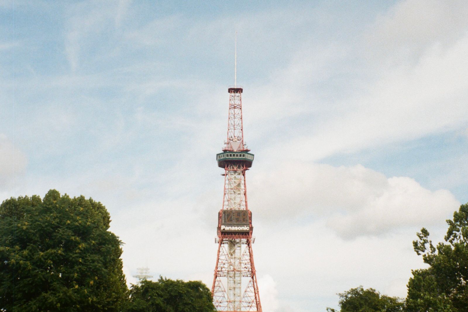 The Sapporo TV Tower rising above the trees of Odori Park on a summer day.