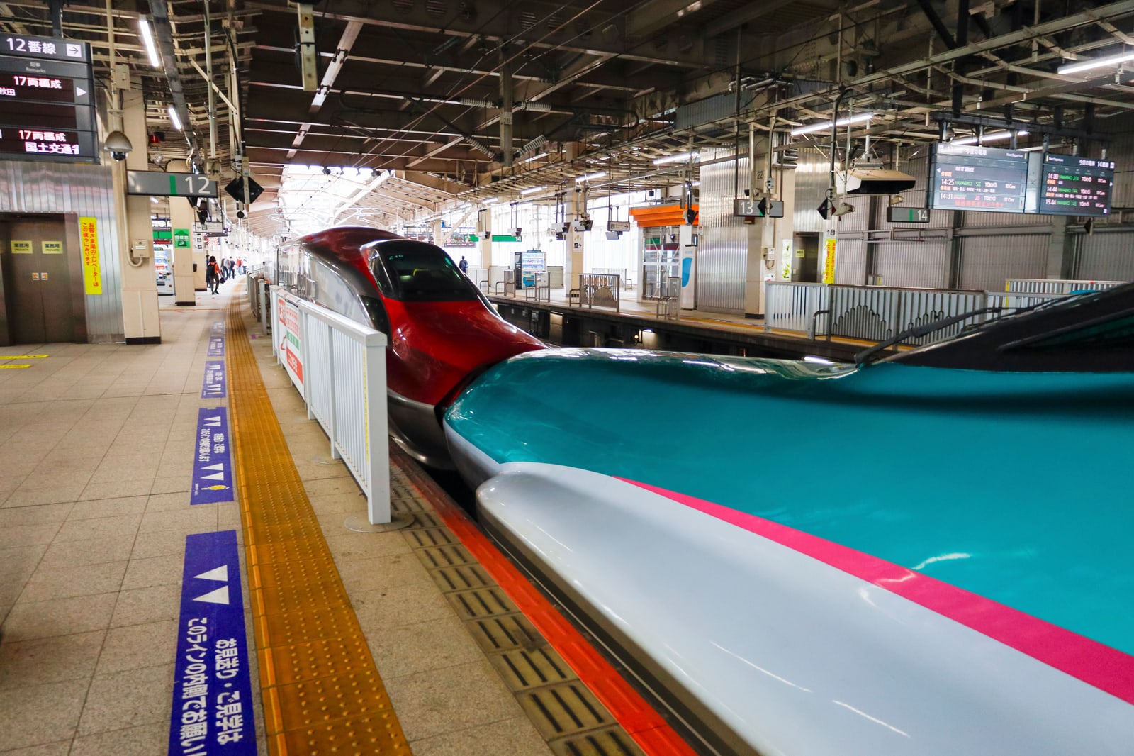 Two Shinkansen trains coupled nose to nose at a station platform, one red and one green and white