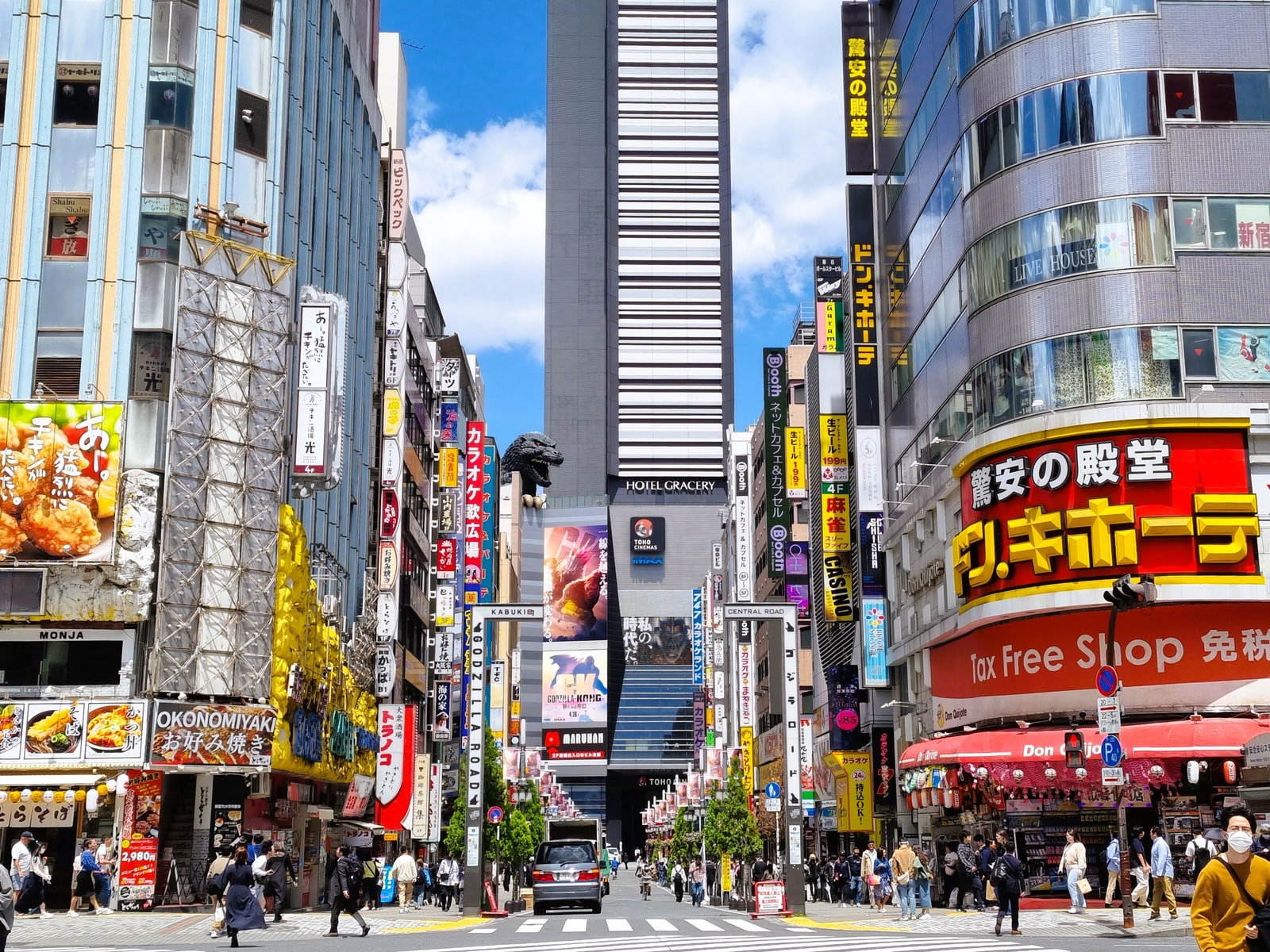 The Godzilla Head above the Hotel Gracery and Toho Cinemas signs at the end of a Kabukicho street, seen in daylight