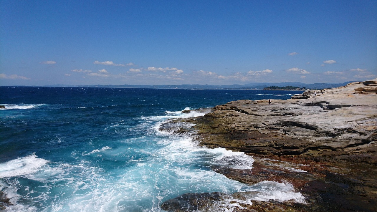 Pale layered sandstone ledges meeting the sea under a blue sky