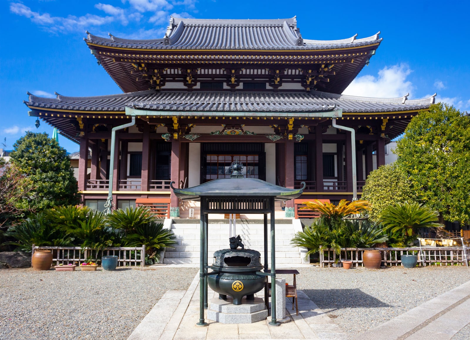 A Buddhist temple's main hall with a bronze incense burner in its forecourt.