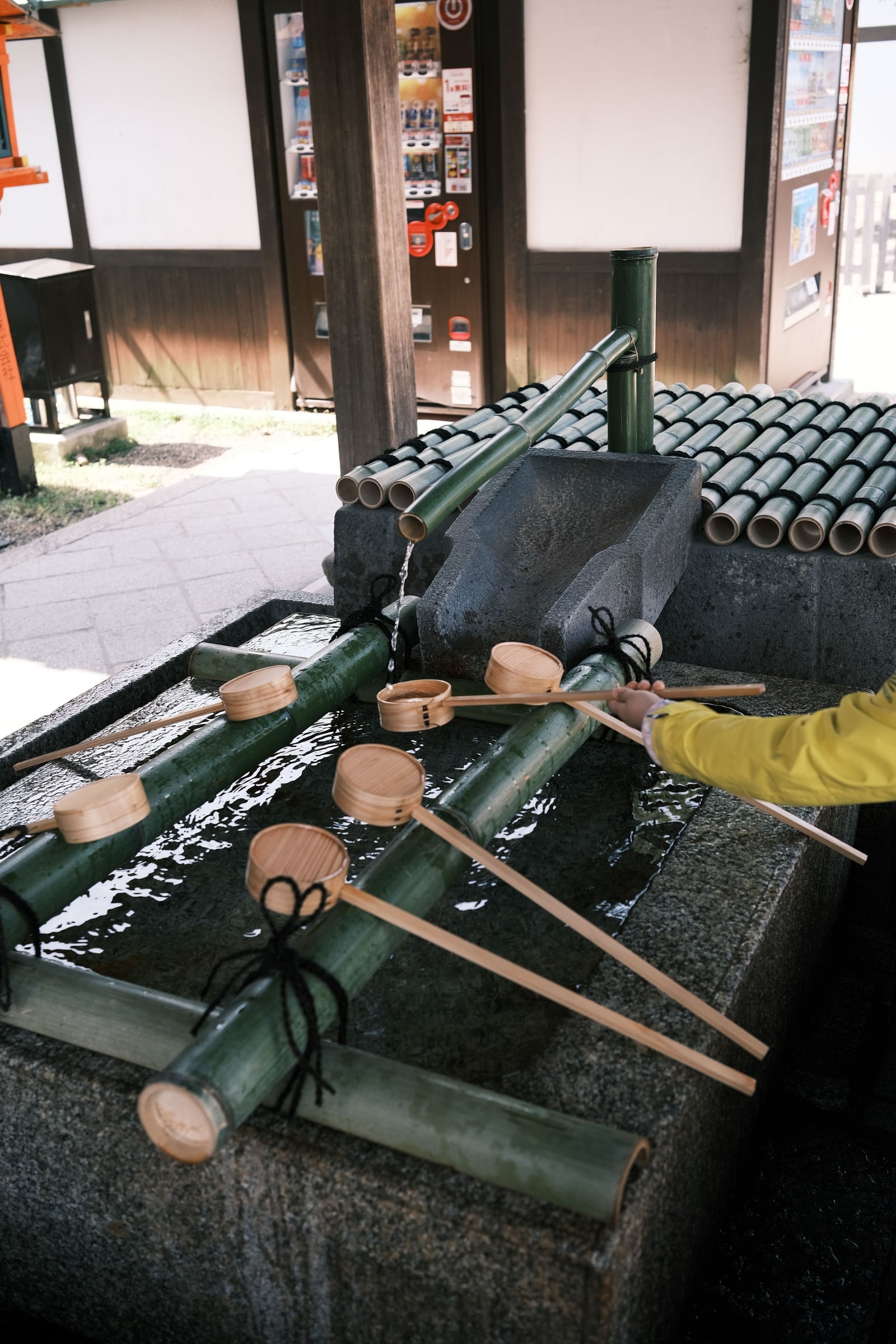A stone chozuya purification basin with wooden ladles in Kyoto.