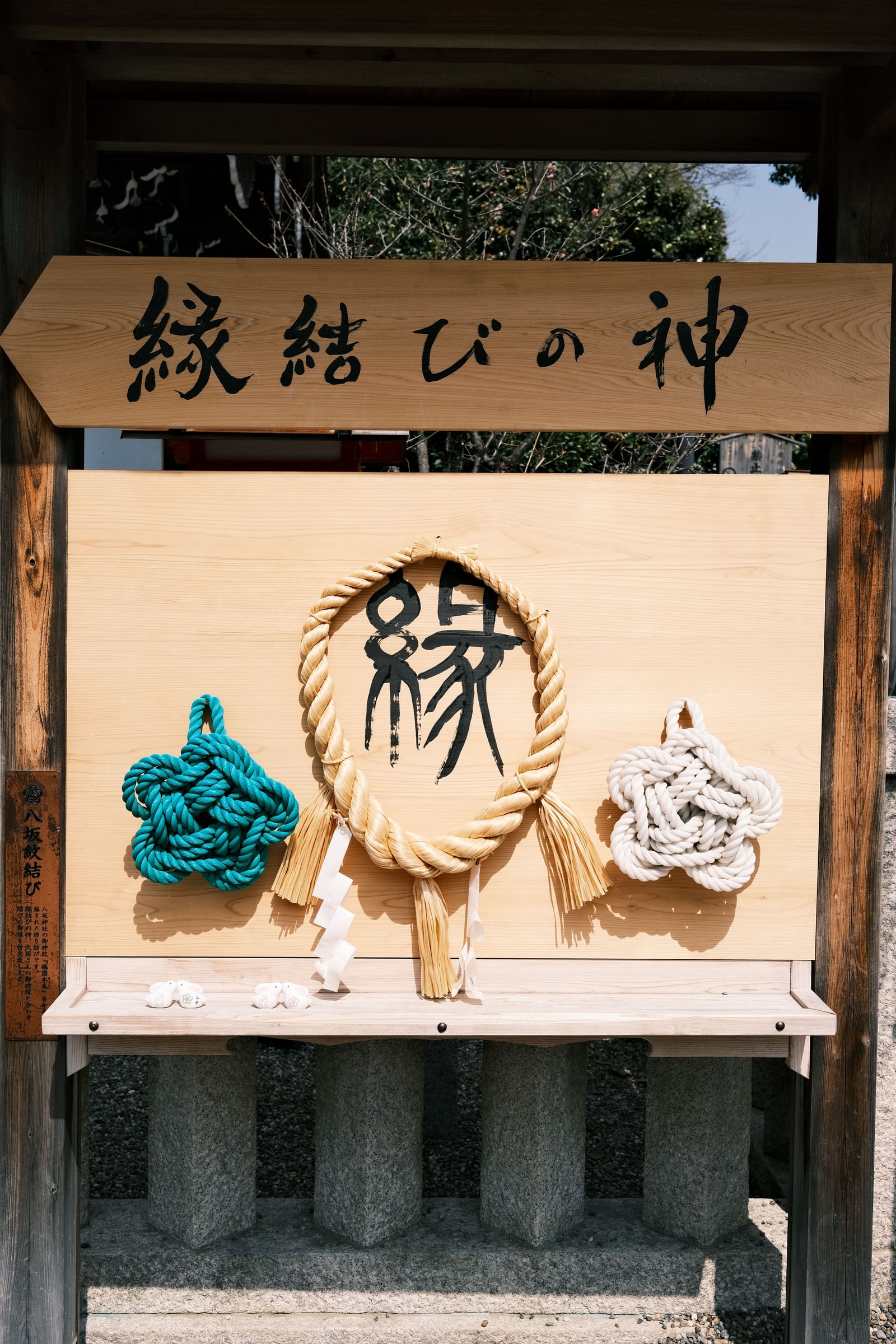 A wooden matchmaking plaque with decorative rope knots at Yasaka Shrine, Kyoto.