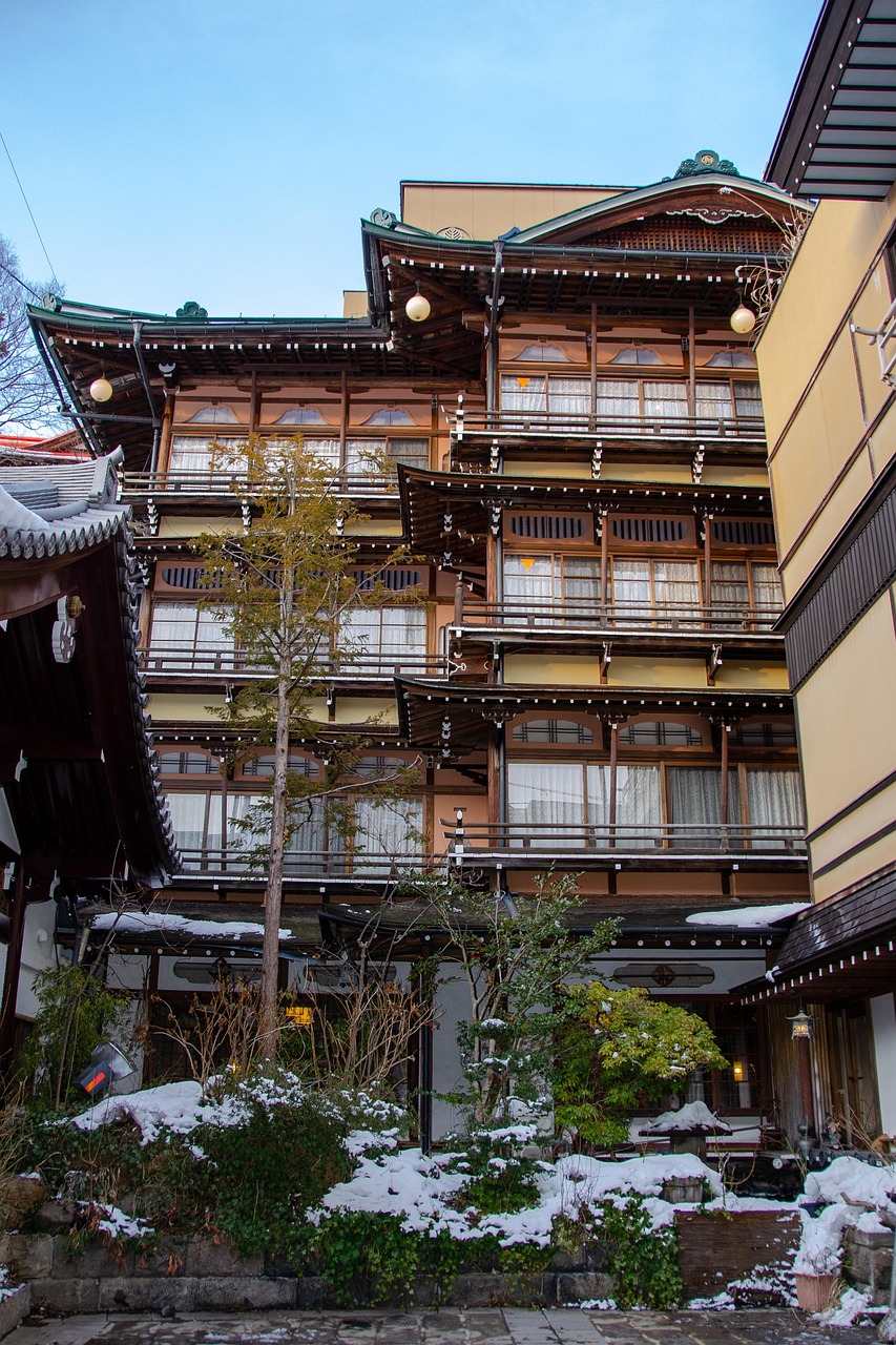 A tall wooden inn with many balconies in Shibu Onsen, a little snow on the ground in front.