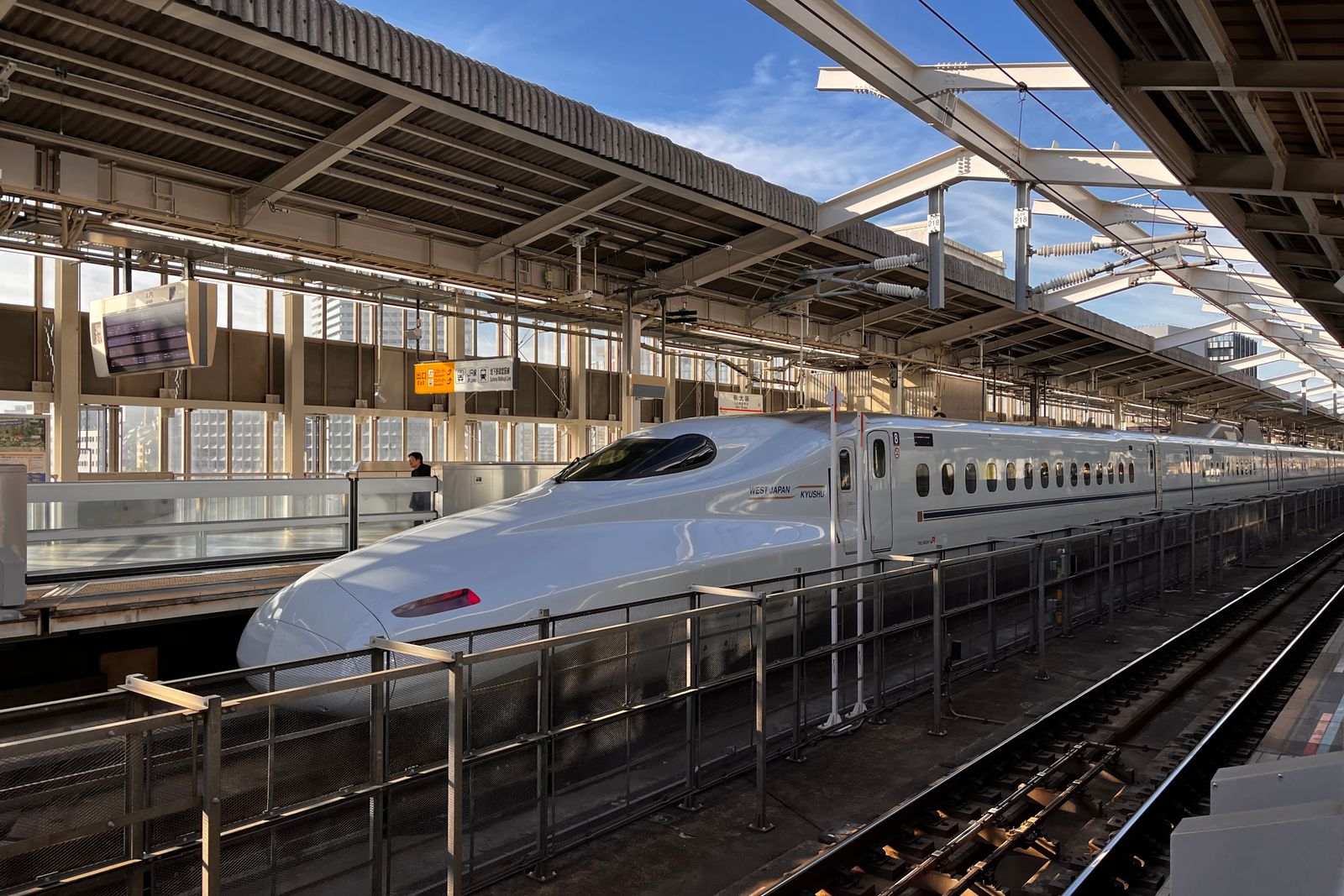 A white N700-series Shinkansen at a Shin-Osaka platform under the trainshed.
