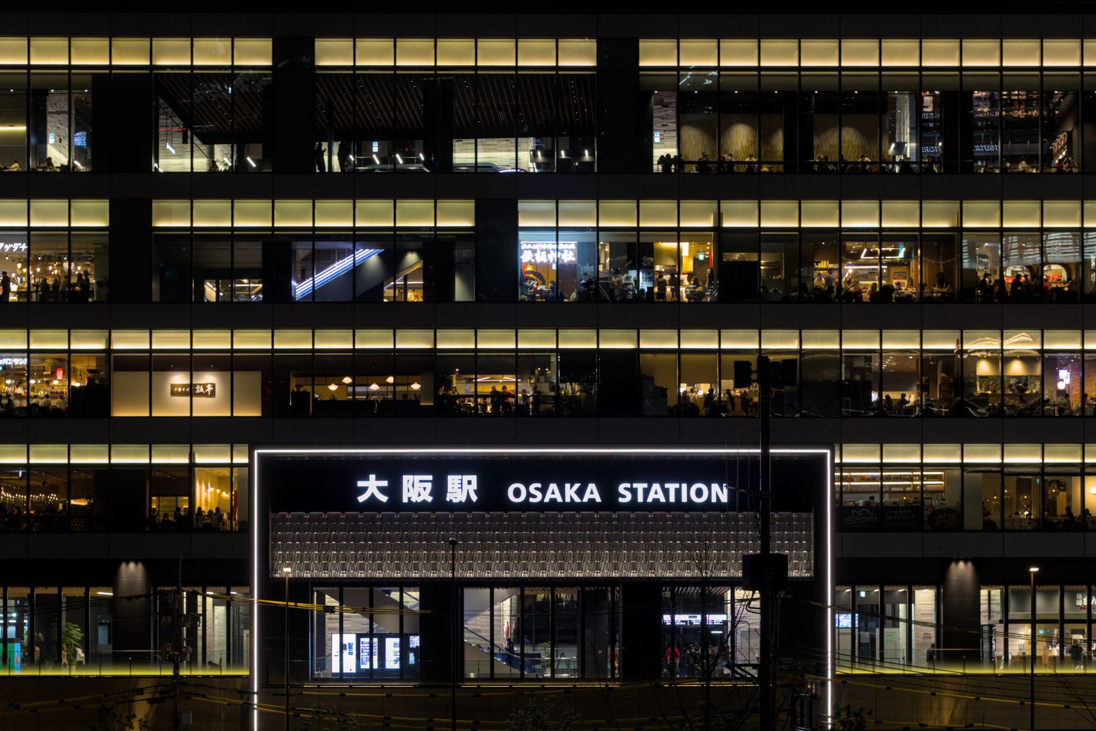 The lit 大阪駅 / OSAKA STATION sign above the station entrance at night.