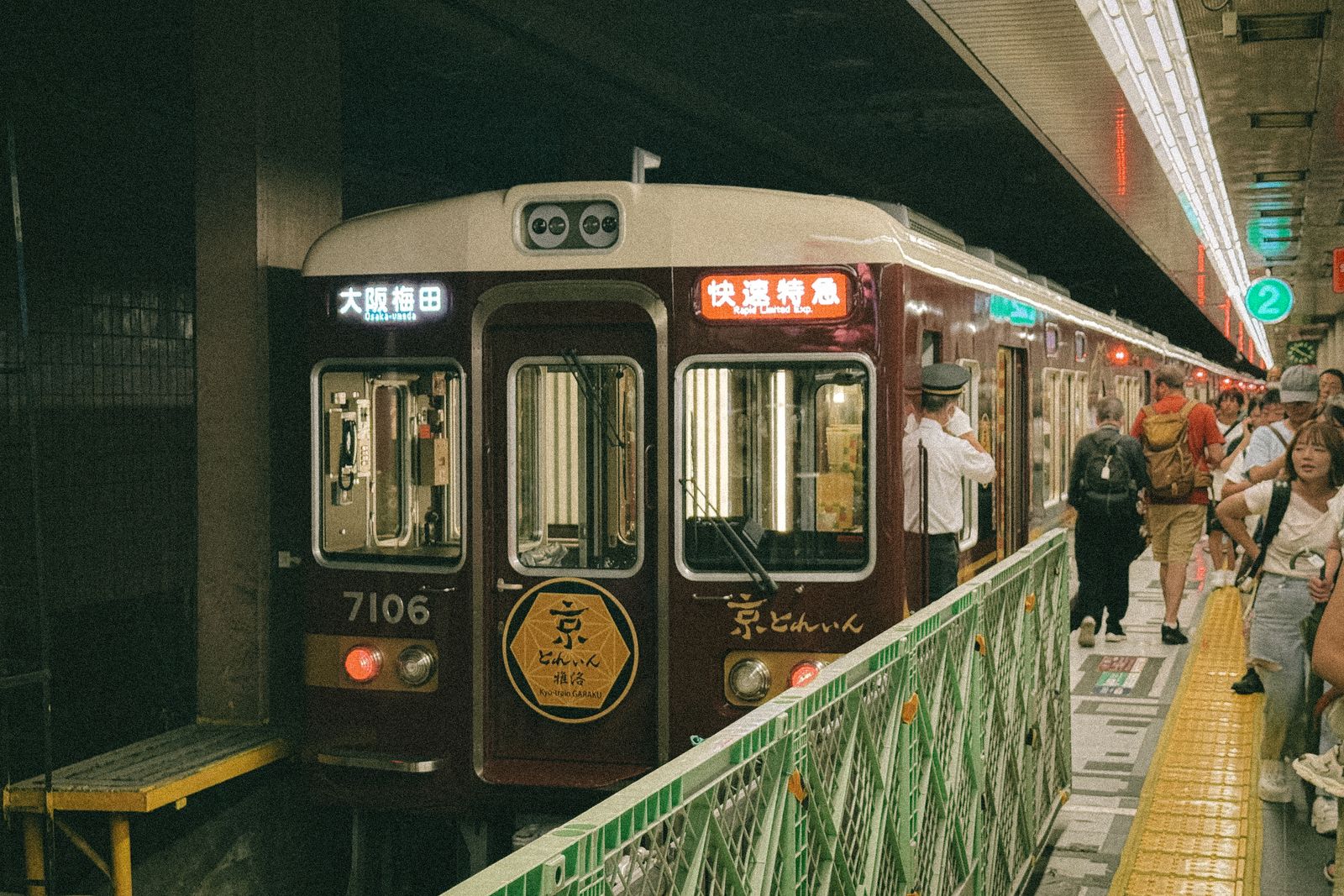 A maroon Hankyu train at Osaka-umeda station, its destination board reading Osaka-umeda and an orange limited express service board above the cab.