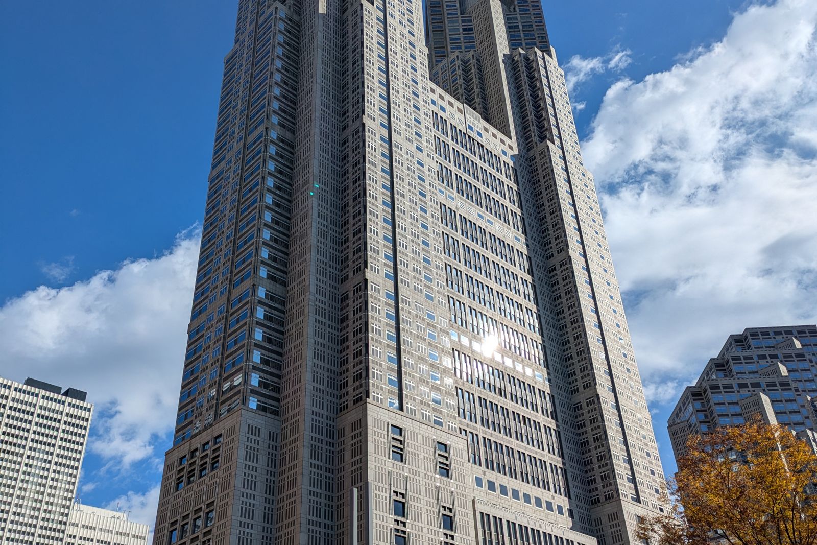 The twin towers of the Tokyo Metropolitan Government Building in Nishi-Shinjuku against a blue sky.