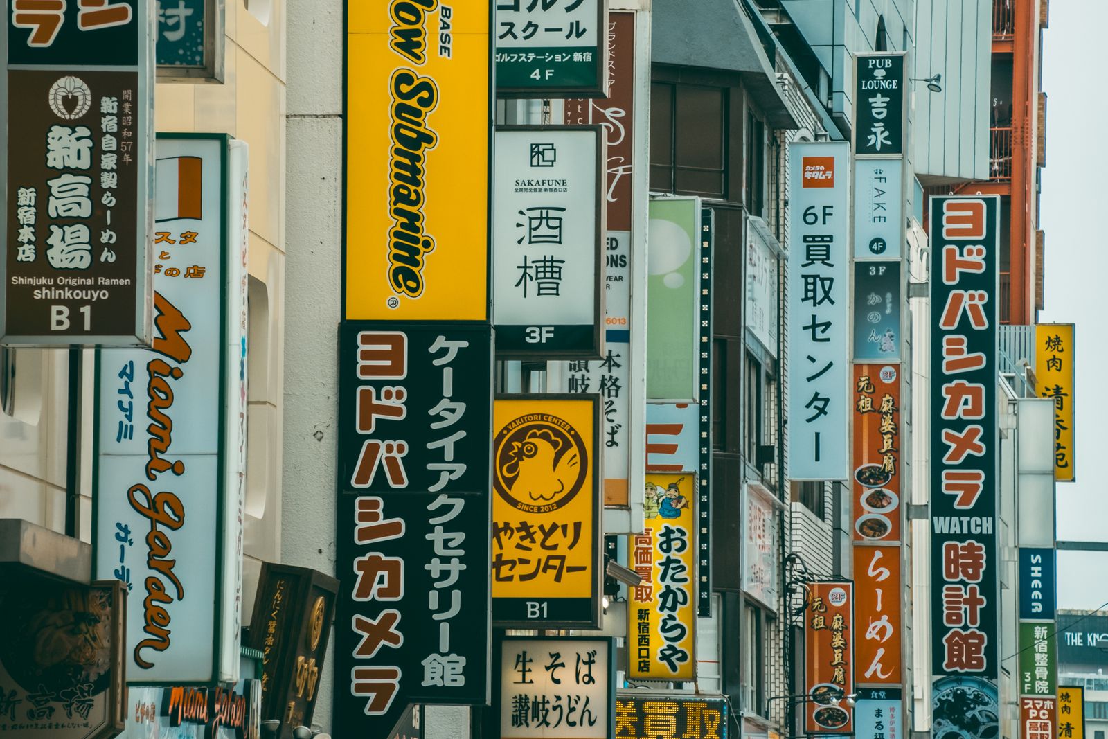 Dense shopfront signage stacked up both sides of a Shinjuku street.