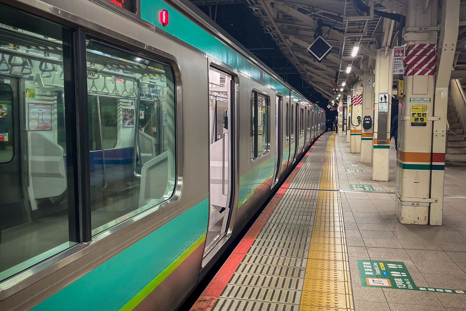 A JR train stopped at a Tokyo platform late at night, doors open and the platform almost empty.