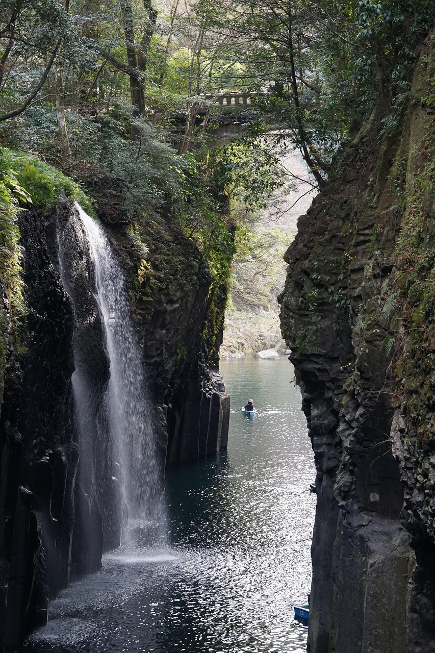 Manai Falls dropping into Takachiho Gorge between walls of columnar rock, a stone arch bridge above