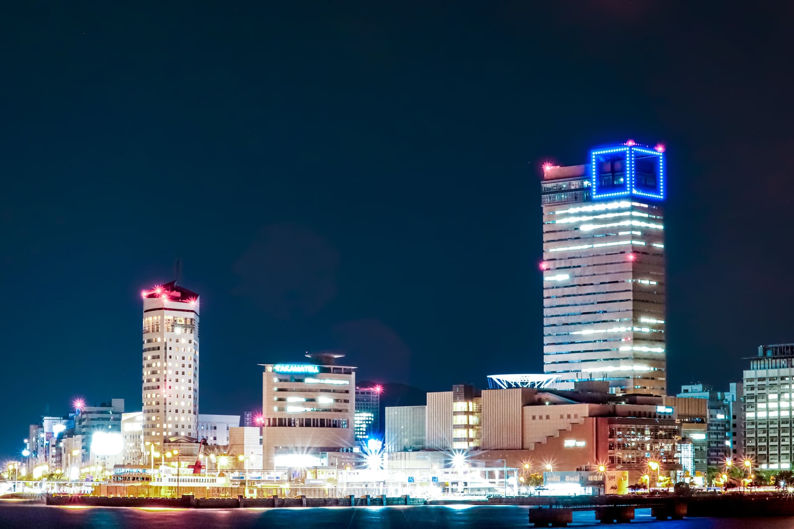 The Takamatsu waterfront at night, with a tall tower lit blue at the top