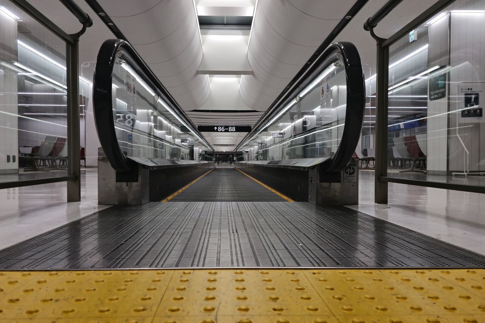 An empty terminal walkway at Narita with a travelator running along it.