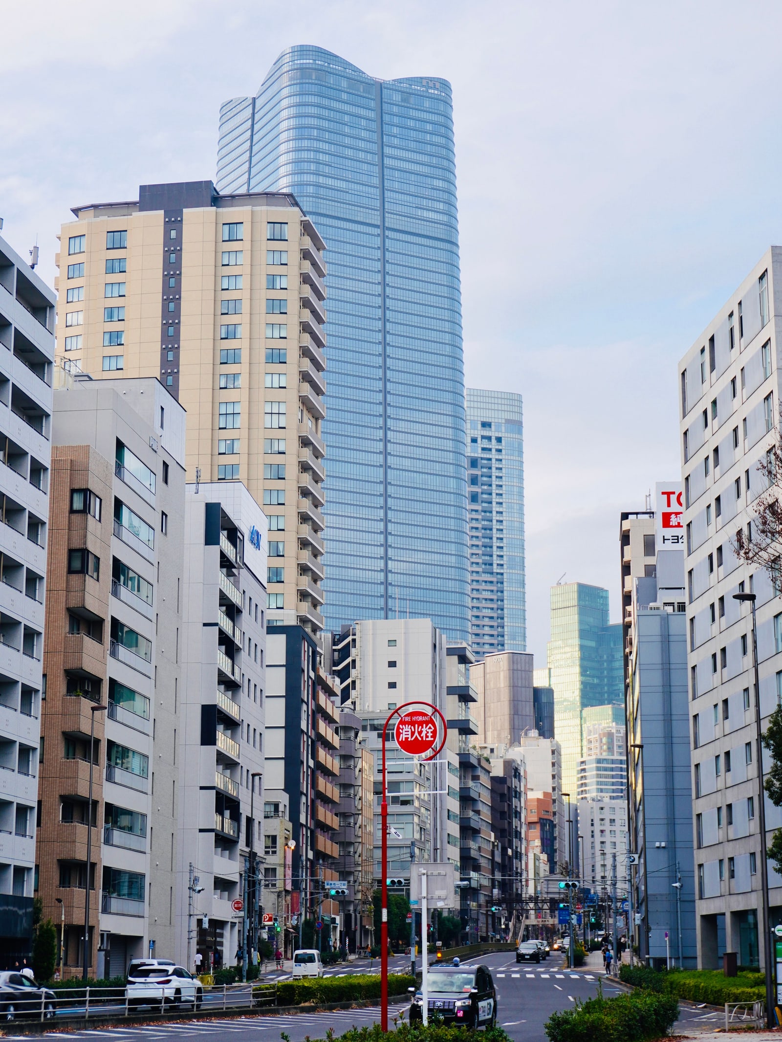 A tall glass tower rising above a Tokyo street lined with apartment blocks.