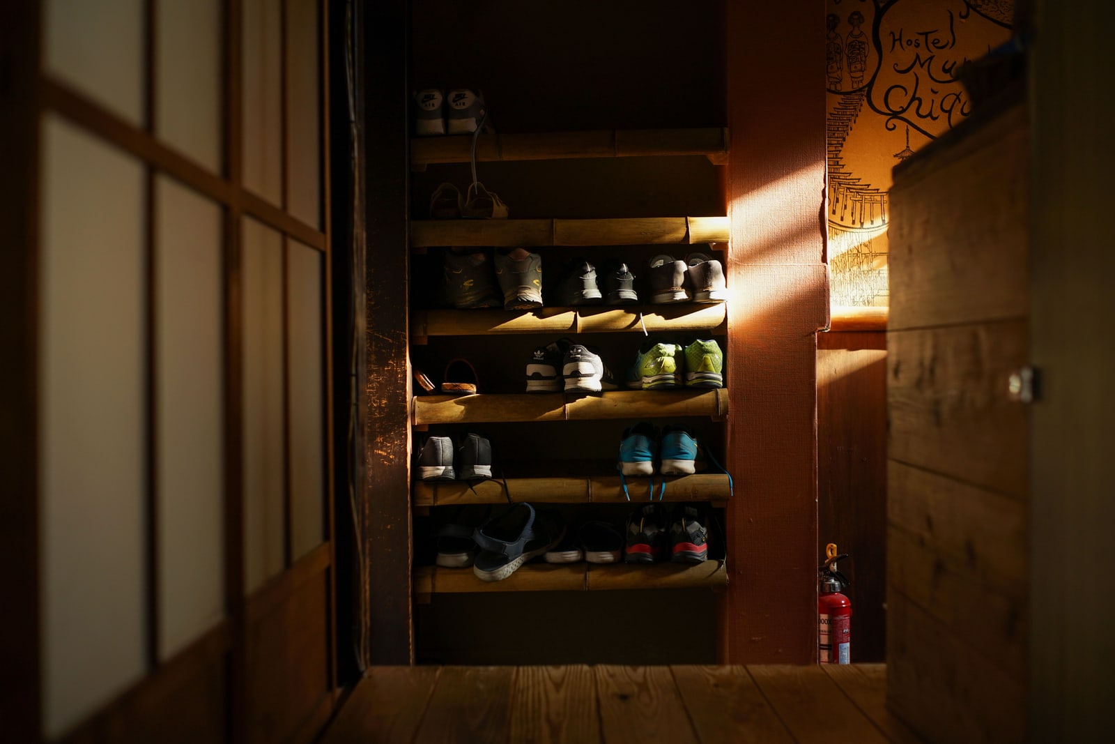 Sneakers left on a wooden shoe rack by an entrance in Japan.