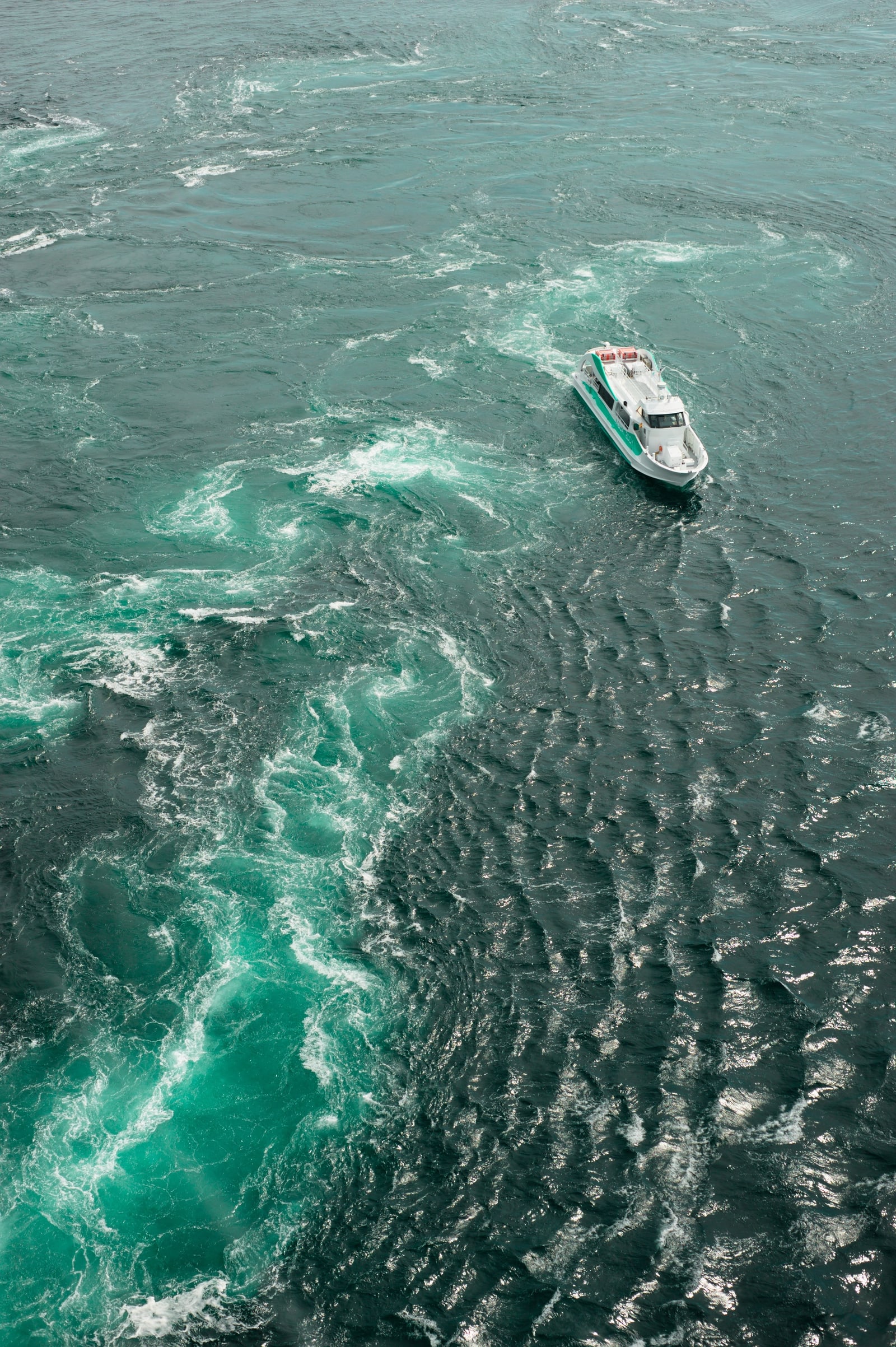 A small sightseeing boat among swirling eddies, seen from high above
