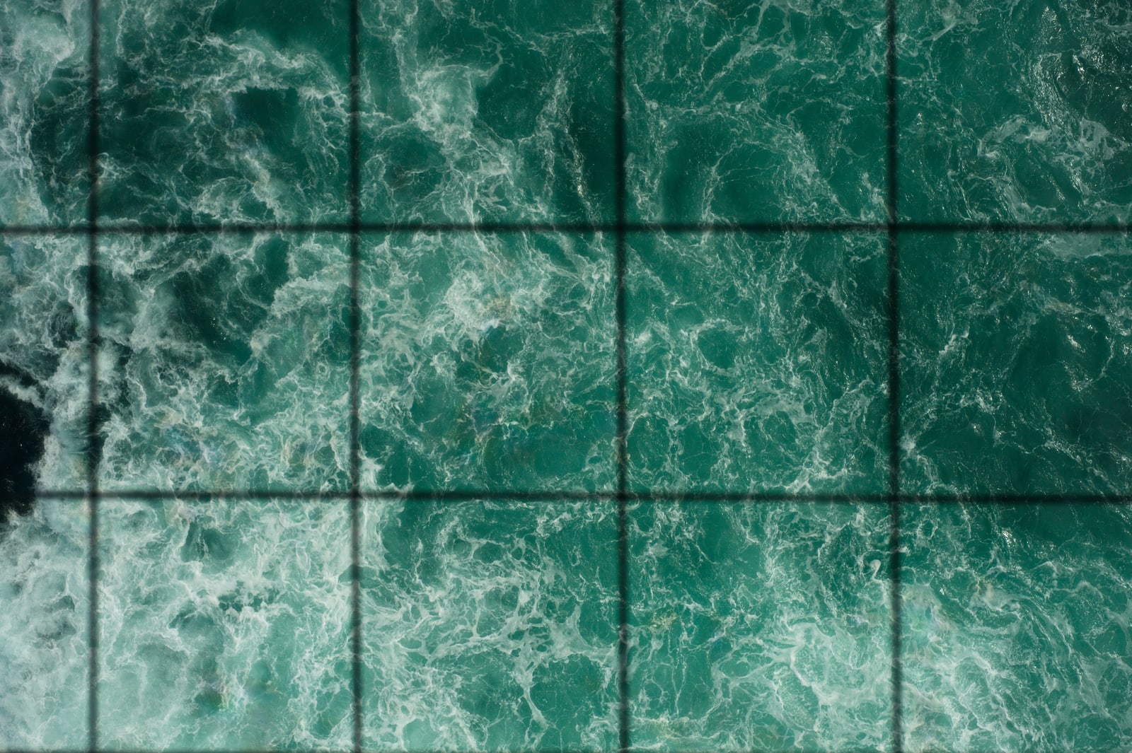 Churning green sea water seen straight down through a glass floor