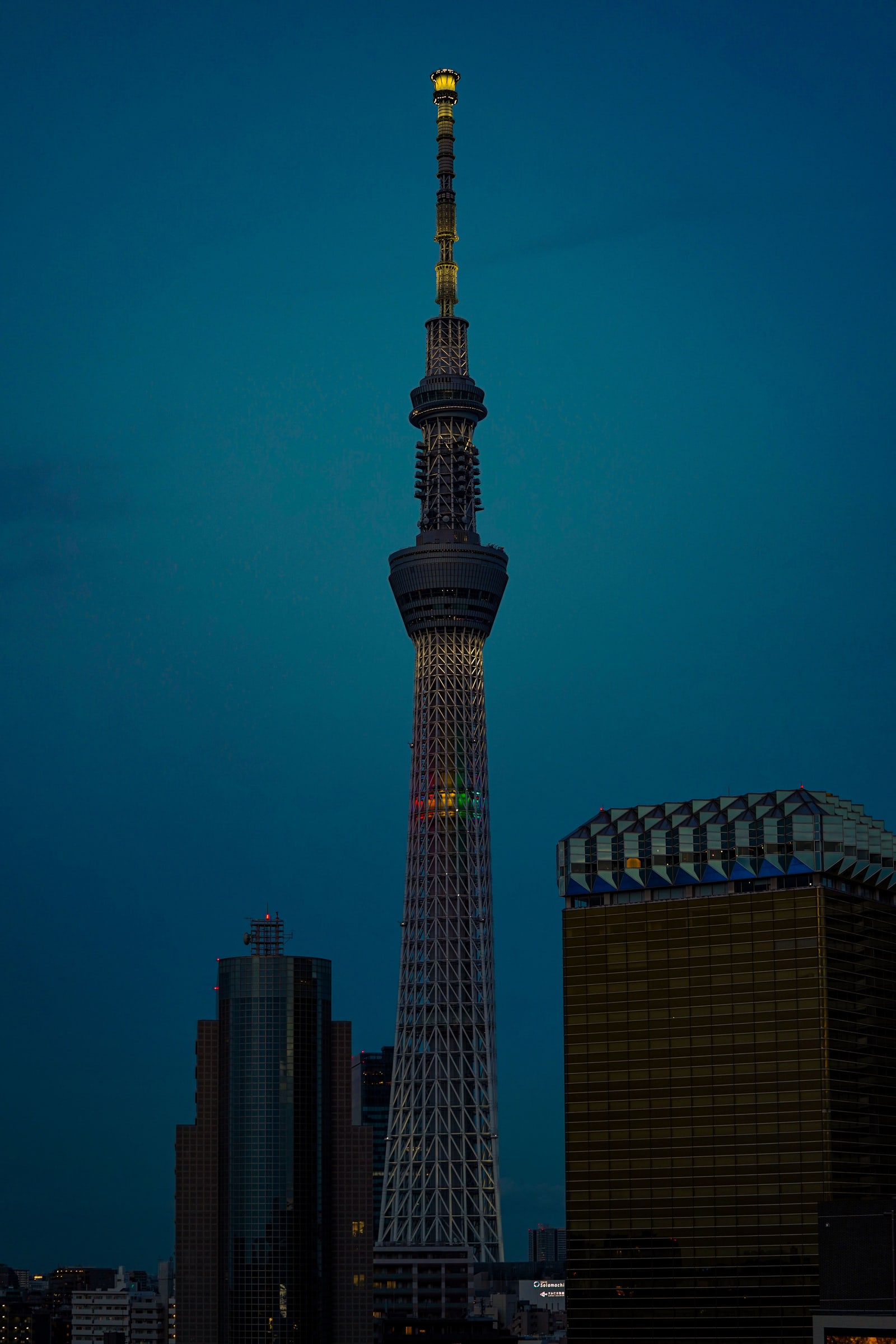 Tokyo Skytree at dusk against a dark blue sky, only the spire lit.