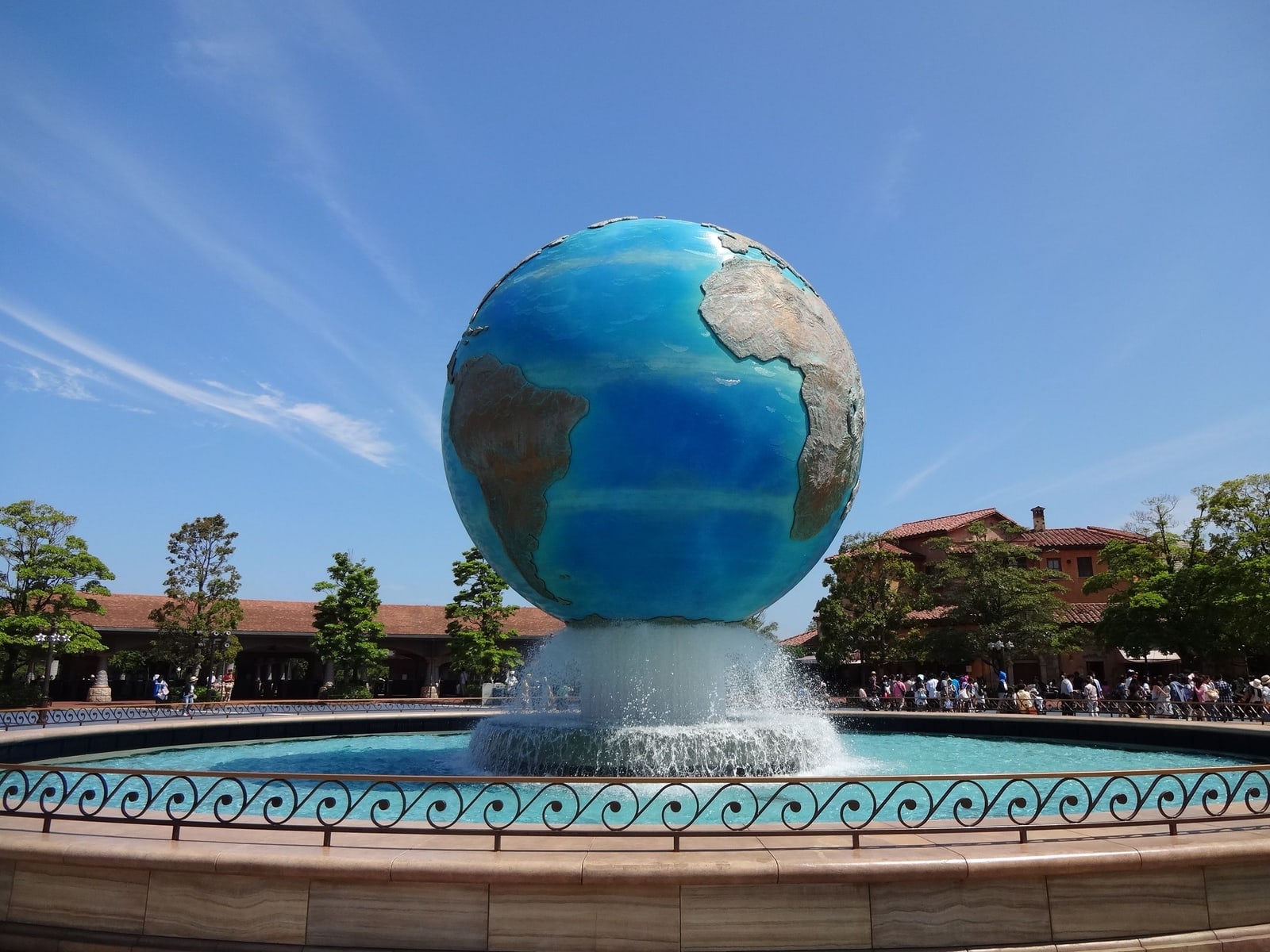 The Earth-globe fountain at the Mediterranean Harbor entrance of Tokyo DisneySea under a clear blue sky.