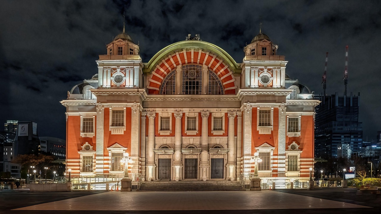 The red-brick Osaka City Central Public Hall lit at night, with its green-roofed central arch and two corner turrets