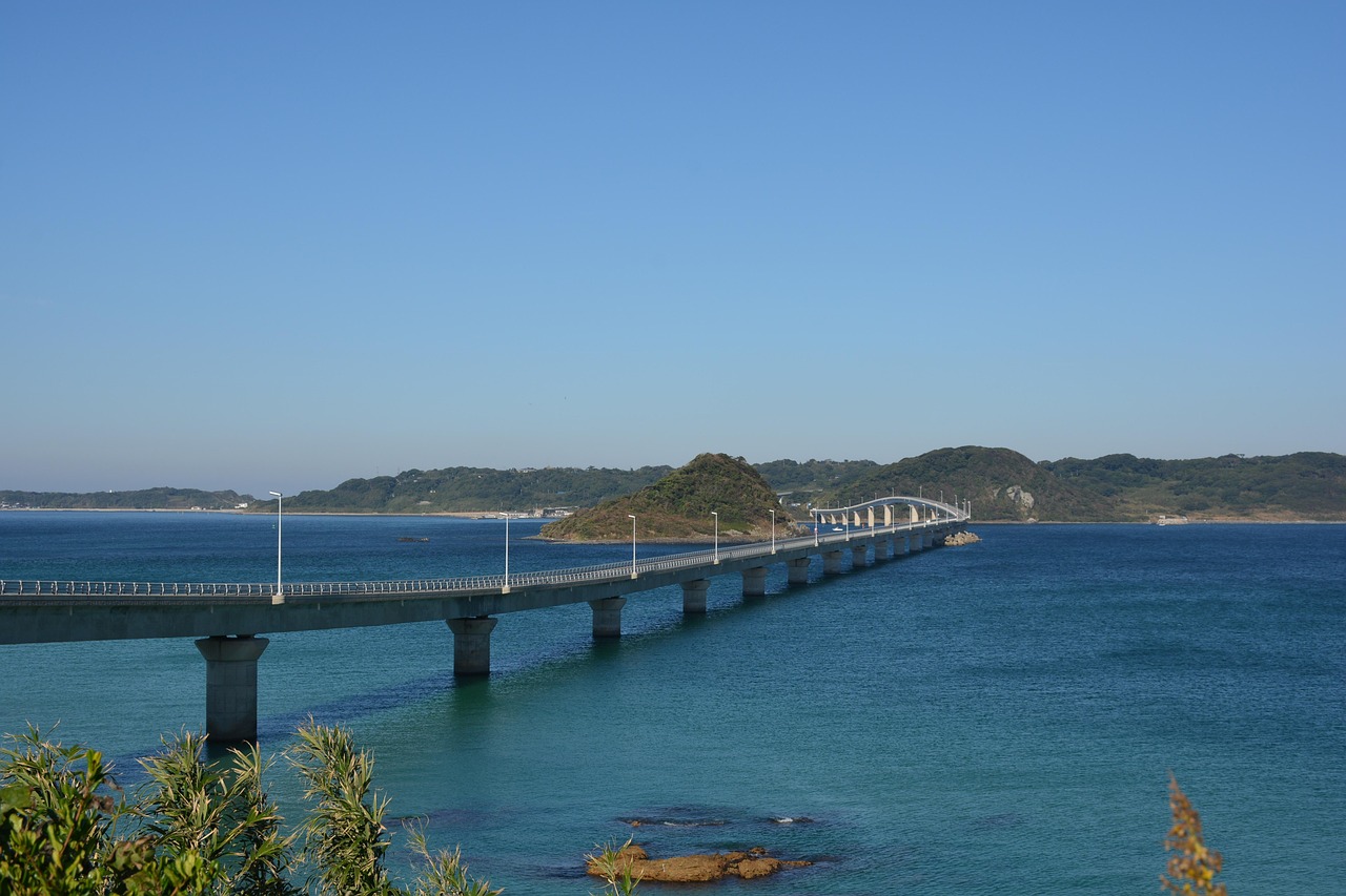 Tsunoshima Ohashi Bridge running low across blue-green sea past a small islet